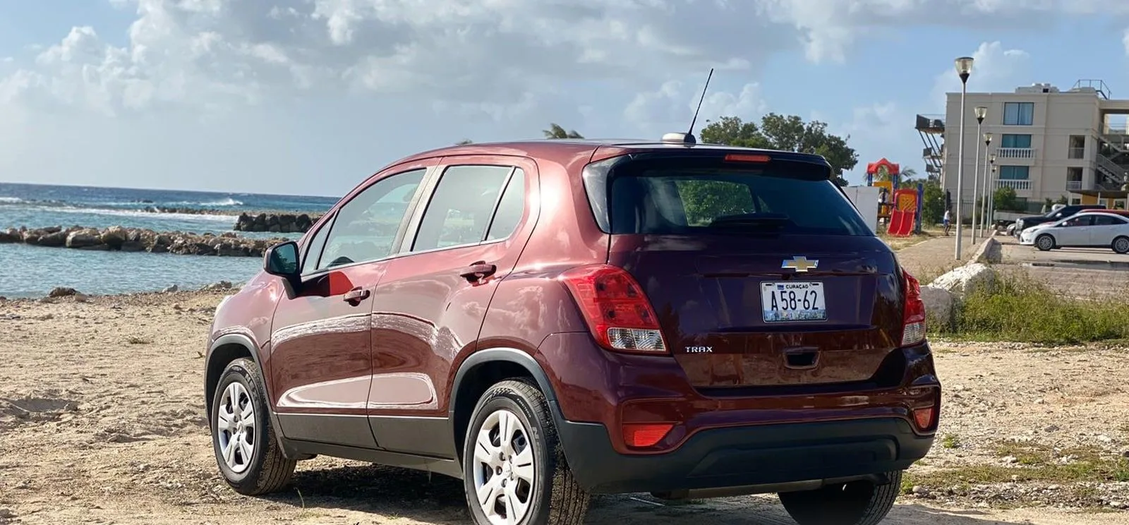 A Dushi Rentals compact SUV parked on the sand beside the sea in Curaçao